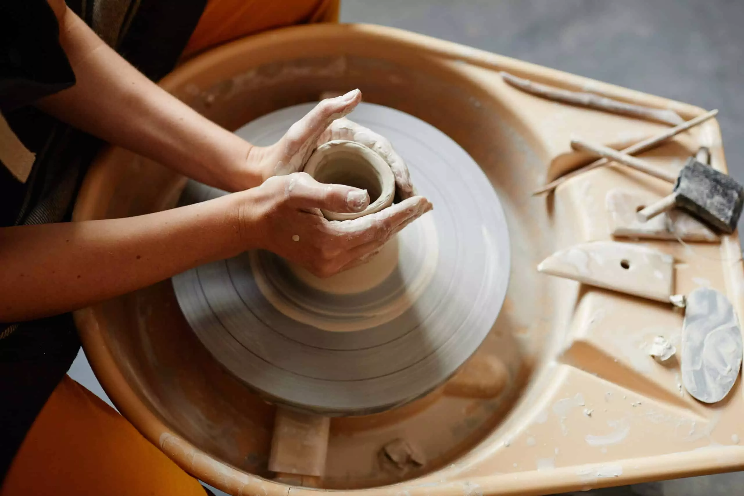 female hands shaping ceramics on pottery wheel